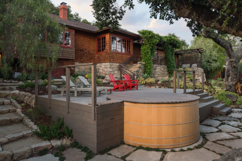 Finished yard with hot tub, red Adirondack chairs, pavers and lush plantings Finished yard with hot tub, red Adirondack chairs, pavers and lush plantings
