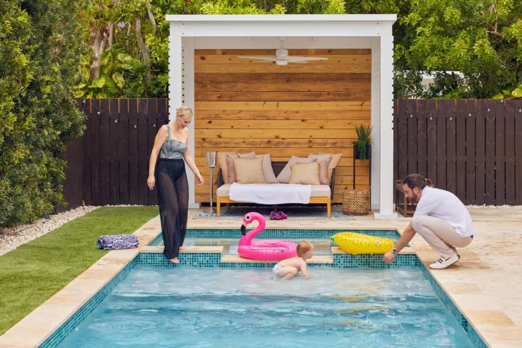 Couple plays with baby in new swimming pool in backyard