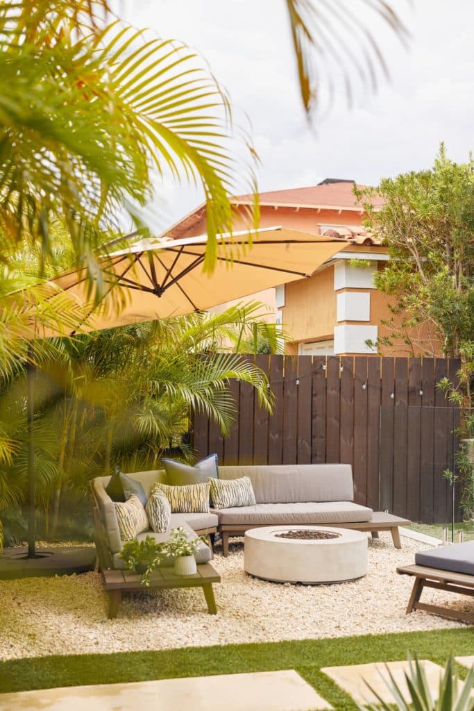 Tropical landscaping surrounding a new outdoor couch and fire pit area
