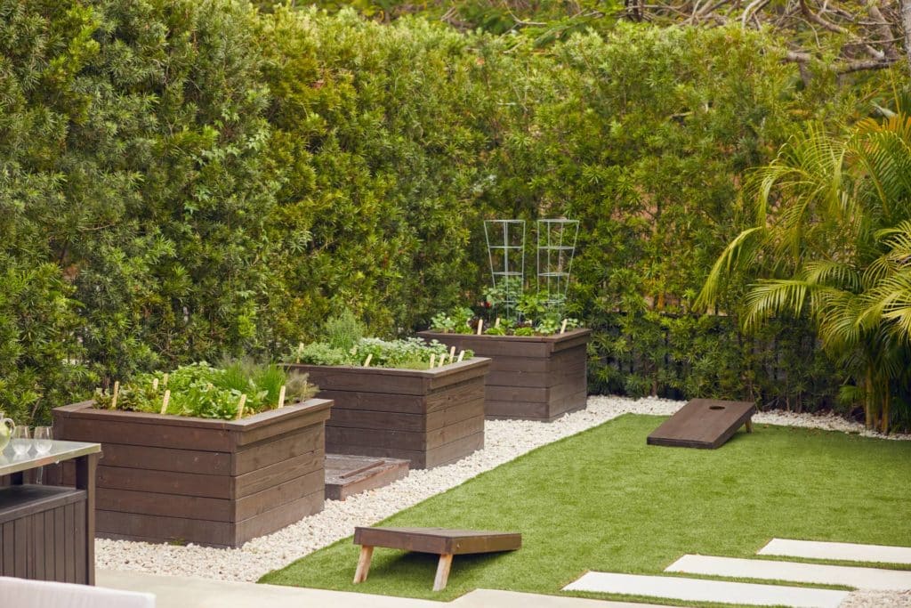 Corner of backyard with new garden beds and cornhole game