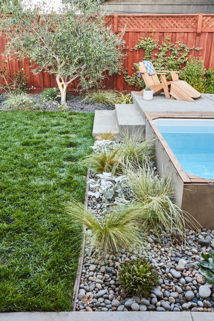 Side view of ornamental grasses planted in river rock alongside the heated plunge pool