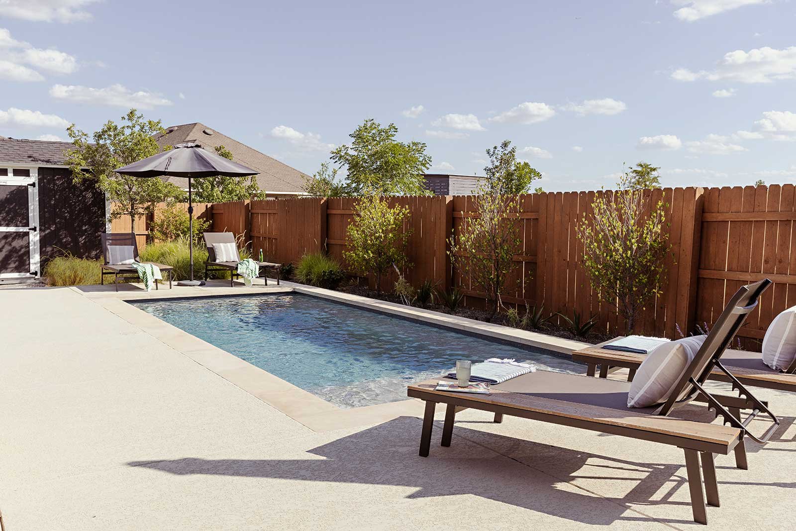 A cluster of grasses and a canopy tree draw attention from the storage shed. So does the pool, whose simple, clean design suits the clients’ modern style.