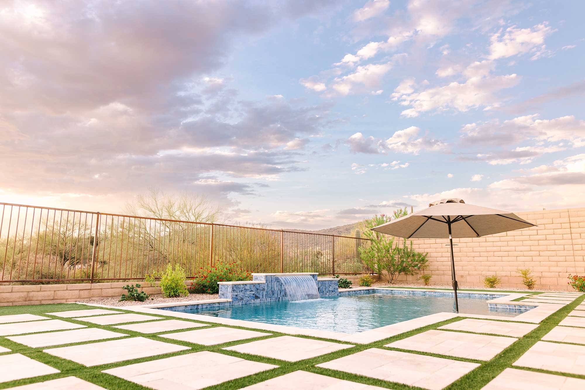 Square “stepper” pavers, typically built from poured concrete, are given a more traditional (and heat-resistant) twist by using travertine.